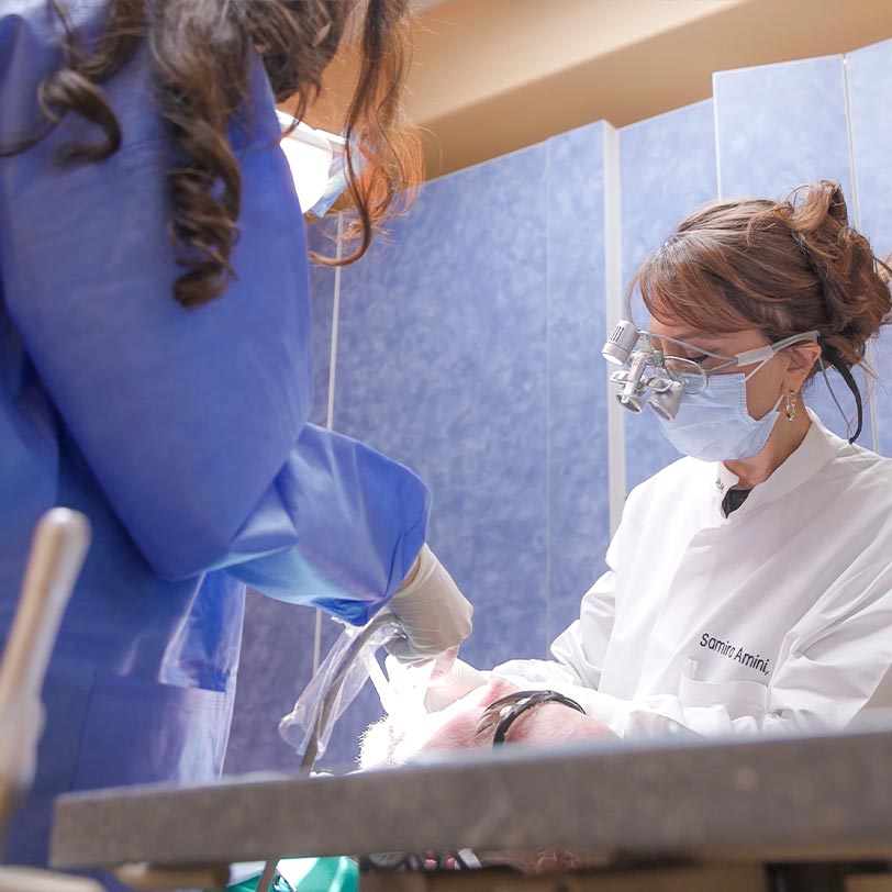 Dr. Amini performing dental work on a male patient in chair